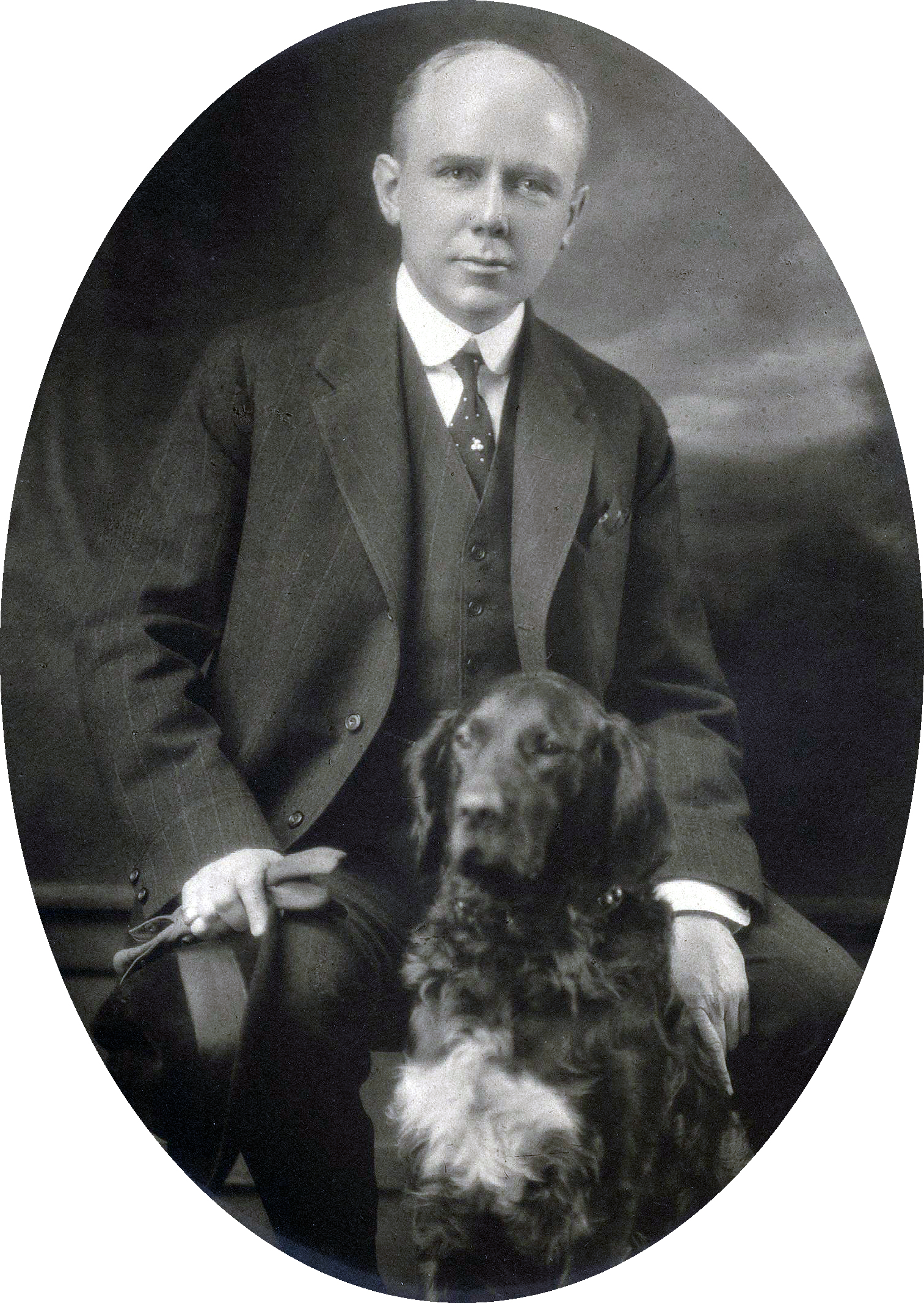 black and white photograph of Percival Proctor Baxter seated, wearing a suit and tie as irish setter, Garry sits in front of him